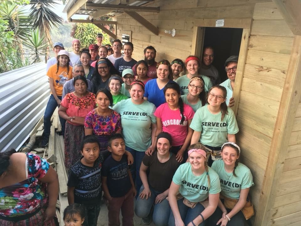 San Raymundo residents stand outside their newly constructed home along with Casas por Cristo workers and volunteers who helped build the house.